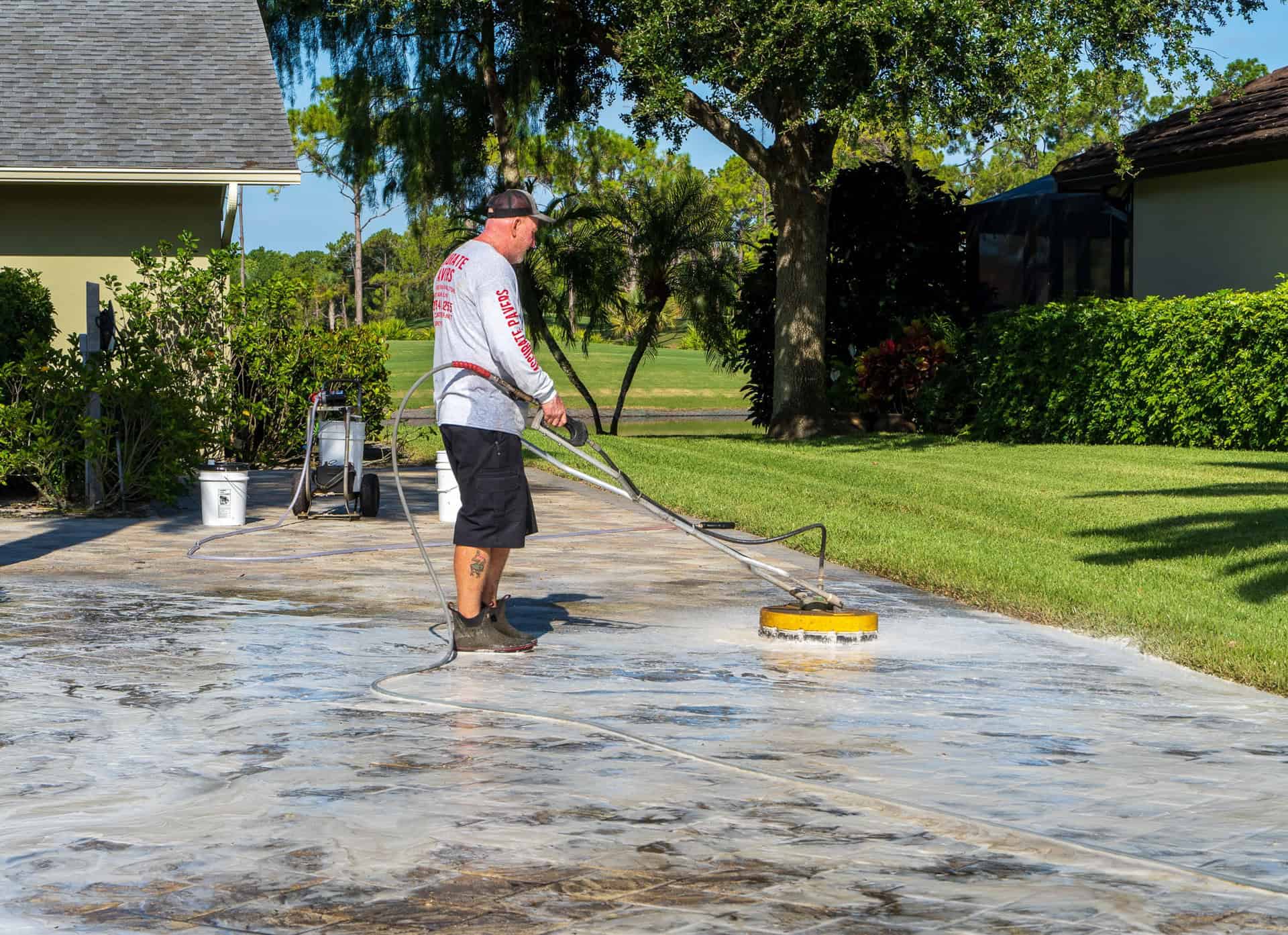 accurate pavers employee pressure washes paved driveway